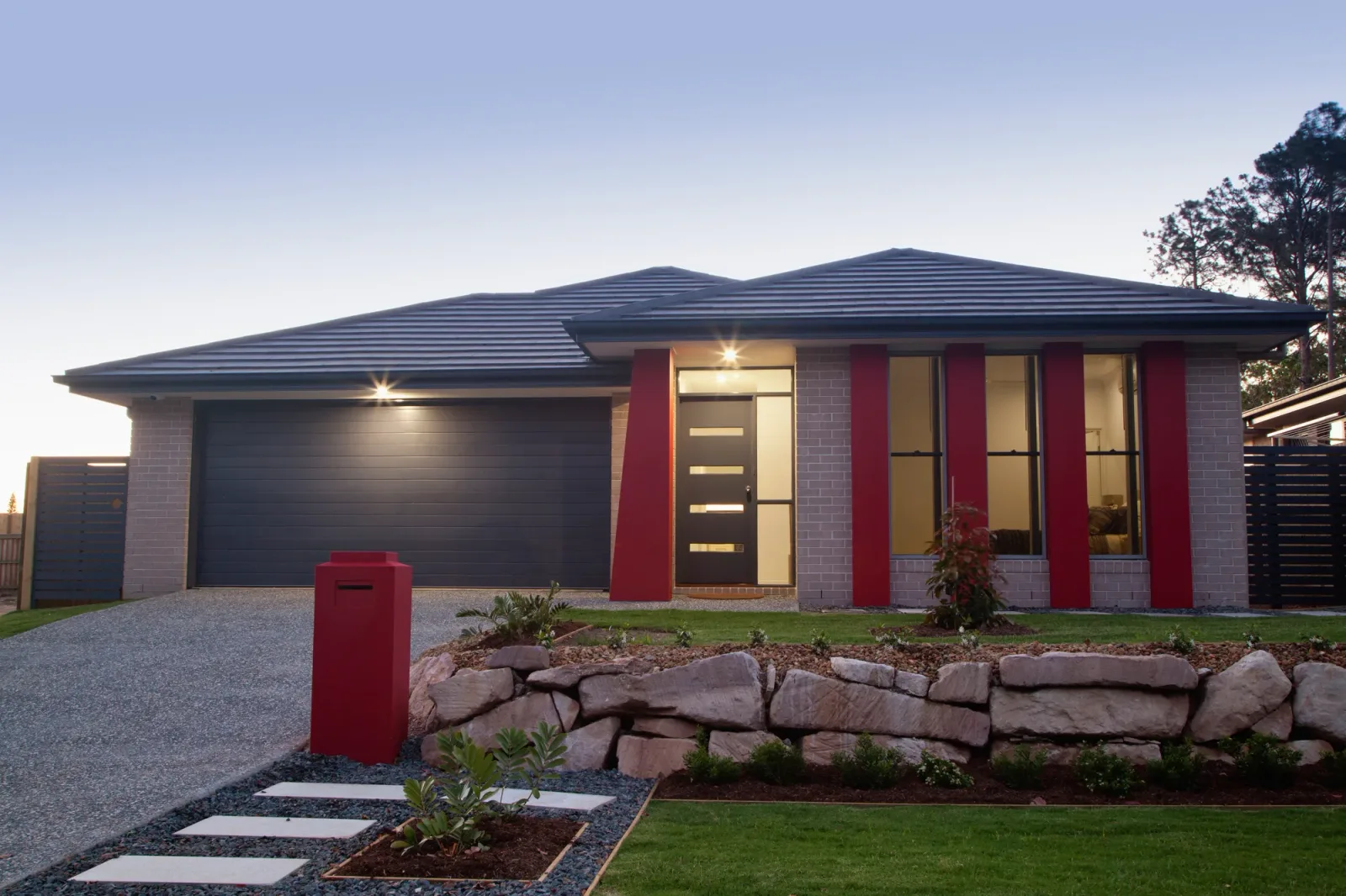 Concrete driveway leading to a home with feature stonework