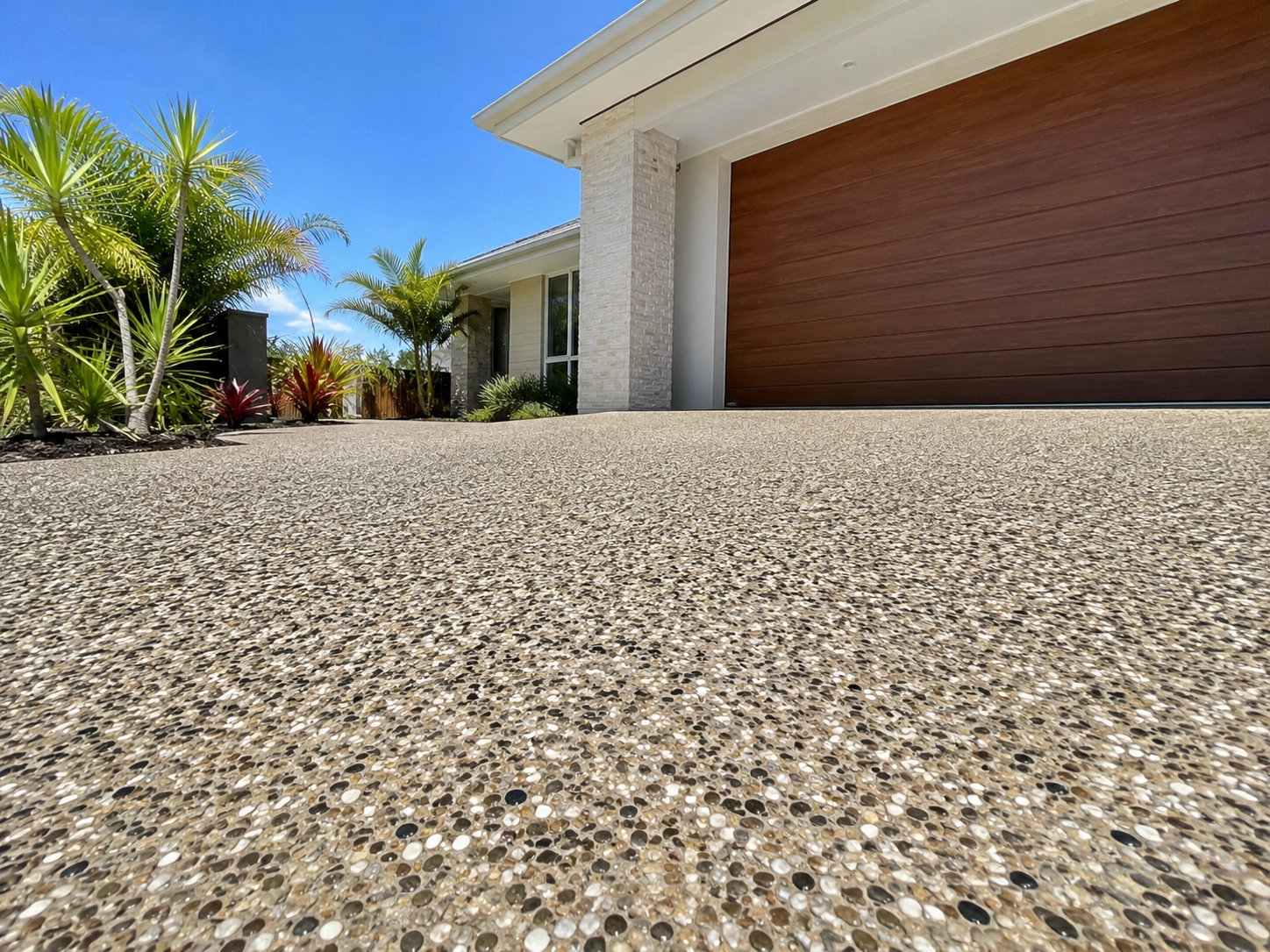 Exposed aggregate driveway finished beside a timber-clad garage